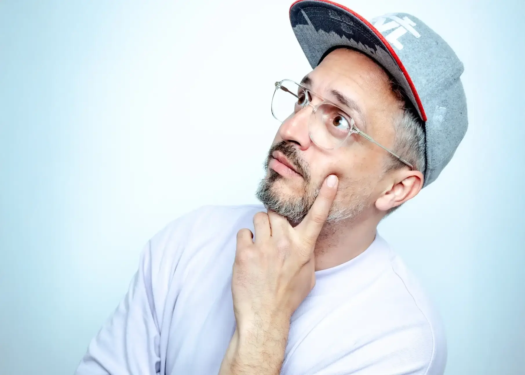 der-physiopath-portrait-entertainer-physiotherapeut Porträt von Der Physiopath mit Brille, Cap und Tattoos, nachdenklicher Blick.